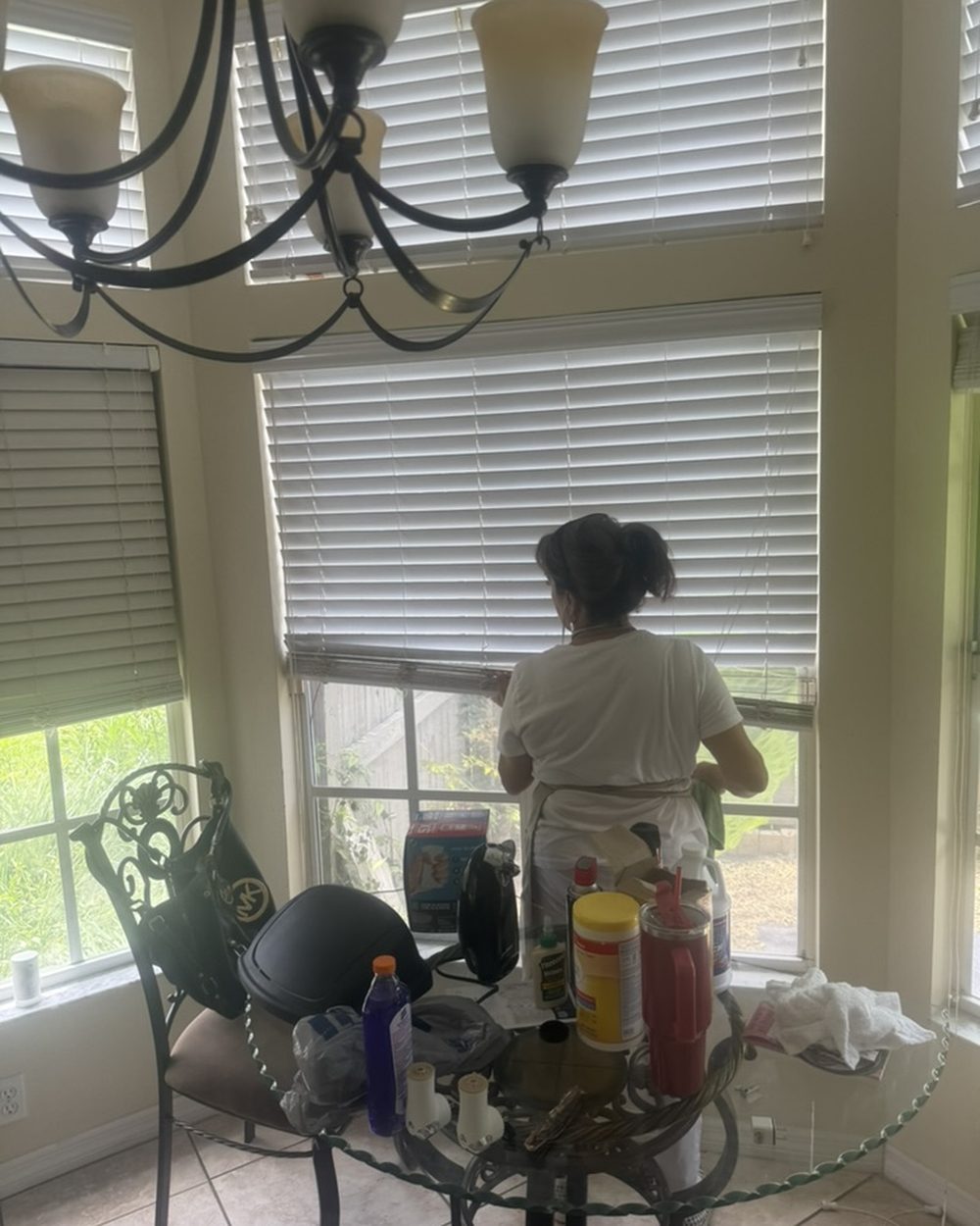 Pure Perfection cleaner wiping window blinds in a breakfast nook during a house cleaning visit, Tampa, FL service area